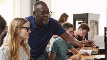 Adult male helping student on computer